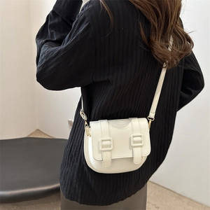 Minimalist white faux leather saddle bag with double buckle straps on shoulder
