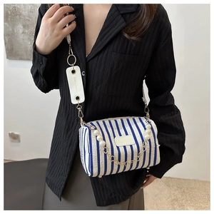 Détail du sac cylindrique à rayures bleues avec chaîne en perles et bandoulière large