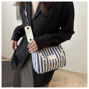 Détail du sac cylindrique à rayures bleu et blanc avec chaîne en perles et étiquette