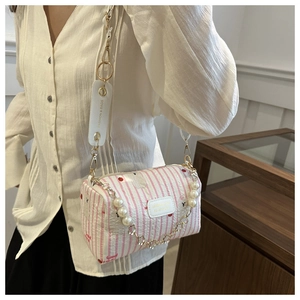 Détail du sac cylindre à rayures roses avec chaîne en perles et bandoulière large