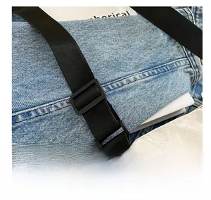 Detailansicht des verstellbaren schwarzen Nylon-Schultergurts mit matter Schnalle auf Denim