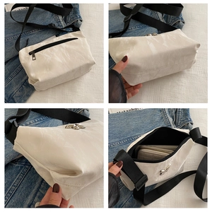 Details einer weißen Plissee-Umhängetasche mit silberner Schmetterlingsschnalle und Gurt