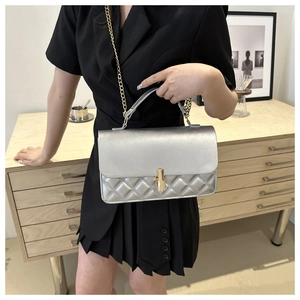 Detail of silver quilted crossbody bag with gold hardware and elegant metal chain strap