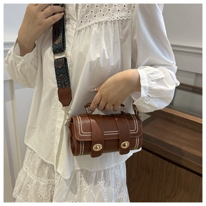 Sac cylindrique marron rétro avec large bandoulière jacquard porté par un modèle