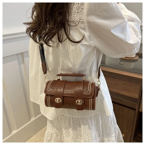Detail of vintage dark brown Boston bag with white rivets and patterned shoulder strap