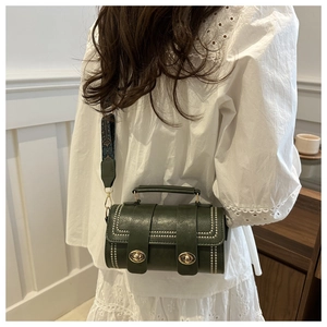 Détail du sac bandoulière cylindrique vert foncé avec rivets et sangle brodée