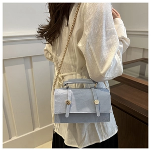 Detail of light blue pleated leather handbag with gold metal buckles and chain strap