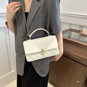 Sac bandoulière matelassé blanc avec poignée et chaîne dorée porté par un mannequin