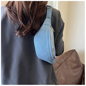 Detail of light blue denim crescent crossbody bag with adjustable wide fabric strap