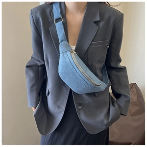 Detailed macro view of light blue denim waist bag with silver zipper and texture