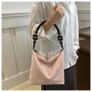 Close-up of pink pleated tote bag featuring vintage dark brown wooden bead handle