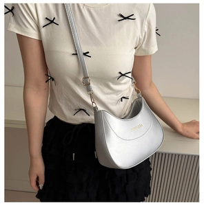 Detail of silver crescent hobo bag with gold logo and adjustable shoulder strap