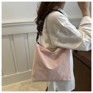 Detail view of pink shoulder bag with unique pleated texture and wooden bead strap