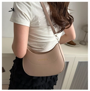 Chic beige faux leather underarm bag shown on shoulder in a minimalist indoor setting