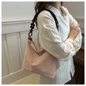 Close-up of pink textured tote bag featuring handcrafted wooden beaded shoulder strap detail