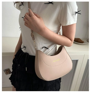 Detail of minimalist cream crescent bag showing smooth matte texture and FANYISSA logo