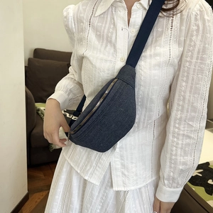 Navy blue denim fanny pack with adjustable strap worn by model in casual setting