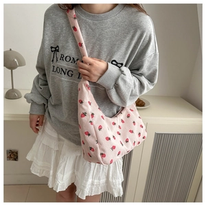 Detail of pink corduroy crossbody bag with strawberry pattern on model in lifestyle setting