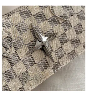 Detailed close-up of textured monogram leather bag with silver star-shaped metal buckle