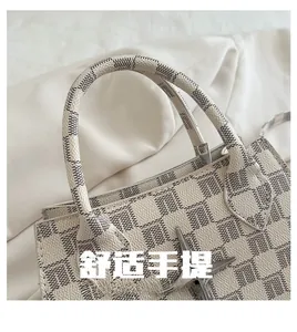 Close-up of the beige checkered handbag with silver star charm and smooth top handle