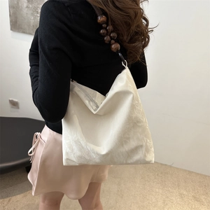 Minimalist white tote bag with textured fabric and unique brown wooden bead shoulder strap