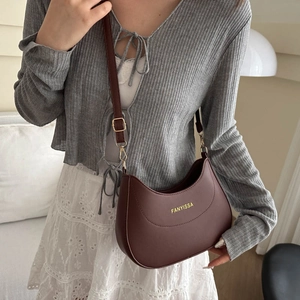 Elegant dark burgundy crescent shoulder bag in matte leather worn by a model in soft light