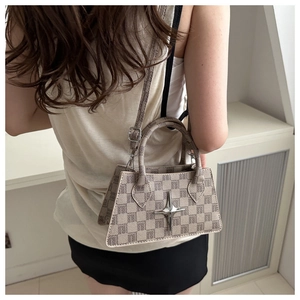 Close-up of checkered trapezoid handbag with metallic star emblem and fabric texture details