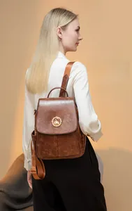 Dettaglio dello zaino vintage marrone con emblema di cigno dorato e trama in ecopelle