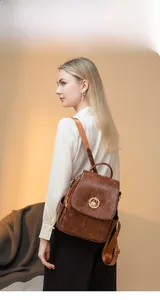 Zaino vintage marrone in finta pelle con emblema di cigno dorato indossato da una modella