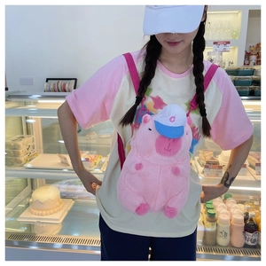 Close-up of pink plush capybara crossbody bag with white cap and pink strap detail
