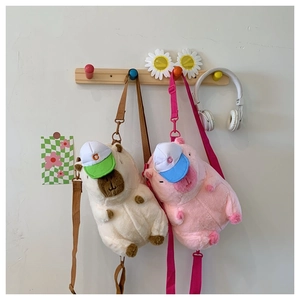 Detail of plush capybara crossbody bags in pink and beige with cute baseball caps