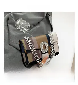 Detail shot of multi-color striped handbag with a crystal buckle and silver chain
