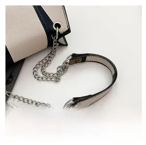 Detail of the canvas shoulder strap with silver chain and gold hardware on the bag