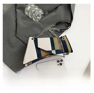 Detail of color-block geometric shoulder bag with metal chain on a grey blazer