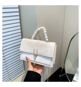 Détail du sac bandoulière blanc en cuir tressé avec poignée perle et chaîne dorée