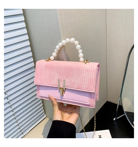 Détail du sac à main rose tissé avec poignée en perles et bandoulière dorée