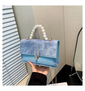 Détail d'un sac à main bleu clair tressé avec anse en perles et fermoir doré chic
