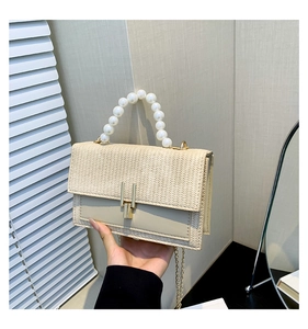 Détail du sac tressé avec poignée en perles et fermoir en métal doré sophistiqué