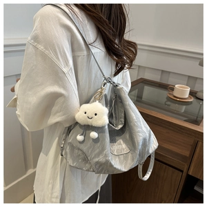 Détail du sac argenté métallisé avec bandoulière chaîne et charm nuage en peluche