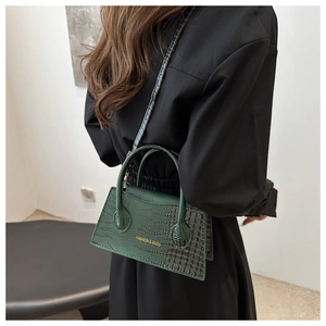 Detail of dark green crocodile texture handbag with gold Fashion and Bags lettering