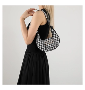 Detailed shot of houndstooth crescent bag with gold H-buckle and black piping trim
