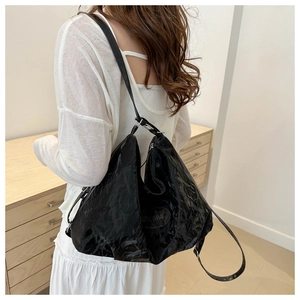 Détail du sac à bandoulière en similicuir noir verni avec texture plissée et chaîne