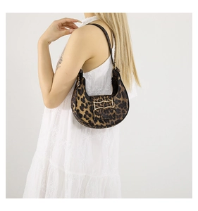 Close-up of leopard print hobo bag with gold metal buckle worn by model in white dress