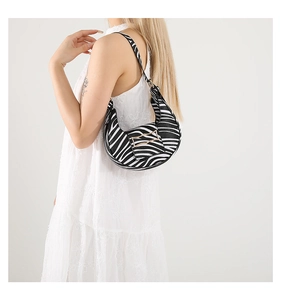Detail view of stylish zebra print crescent shoulder bag with golden buckle and strap