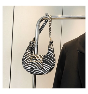 Detail of zebra print crescent shoulder bag with a gold rectangular buckle and leather strap