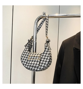 Detailed view of black and white houndstooth crescent bag with gold metal buckle