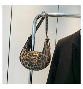 Detailed close-up of leopard print shoulder bag with gold metal buckle on silver hanger