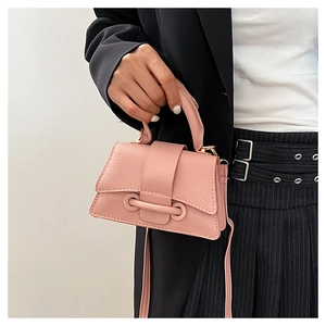 Detailed view of pink lychee leather handbag held by model with elegant gold hardware