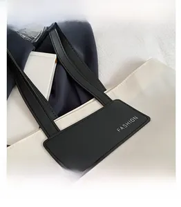 Detail view of the cream tote bag with black strap and a FASHION decorative label