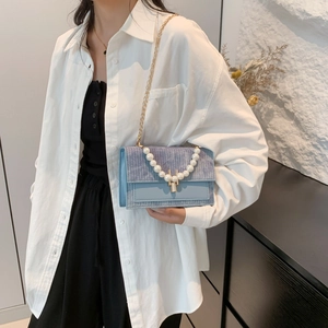 Sac bandoulière bleu clair avec texture tissée, chaîne dorée et anse en grosses perles